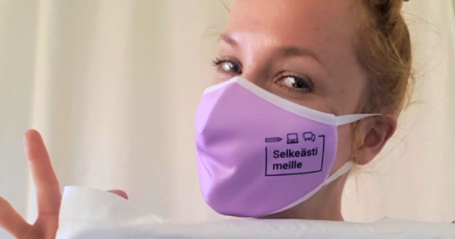 Terhi Tommila maski kasvoillaan. Kasvomaskissa on Selkeästi meille -hankkeen logo.