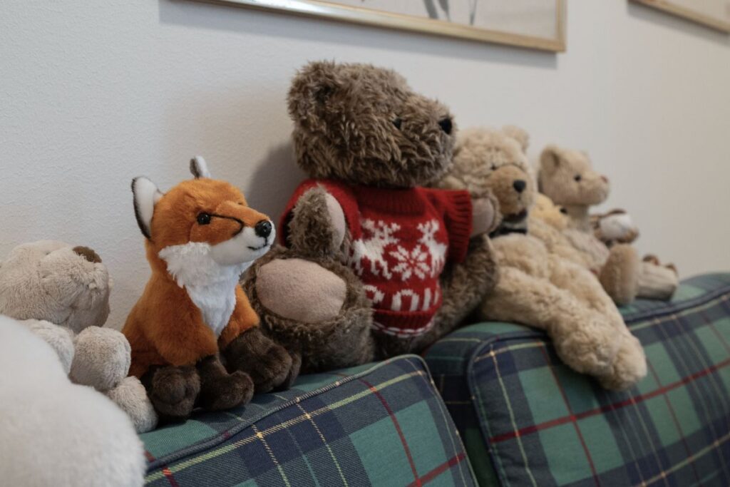 Erilaisia pehmoeläimiä kasattuna sohvan selkänojalle.