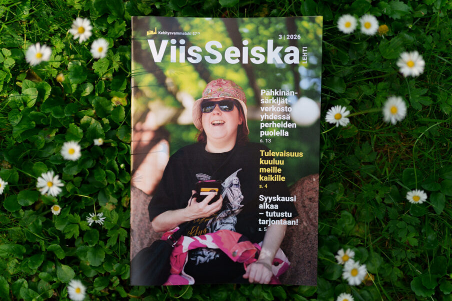 ViisSeiska-lehti 3/2026 vihreällä nurmikolla, jossa kasvaa valkoisia kukkia.
